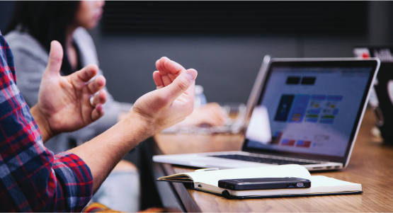 Mortenson team member's hands moving in front of a computer screen in the middle of a conversation.